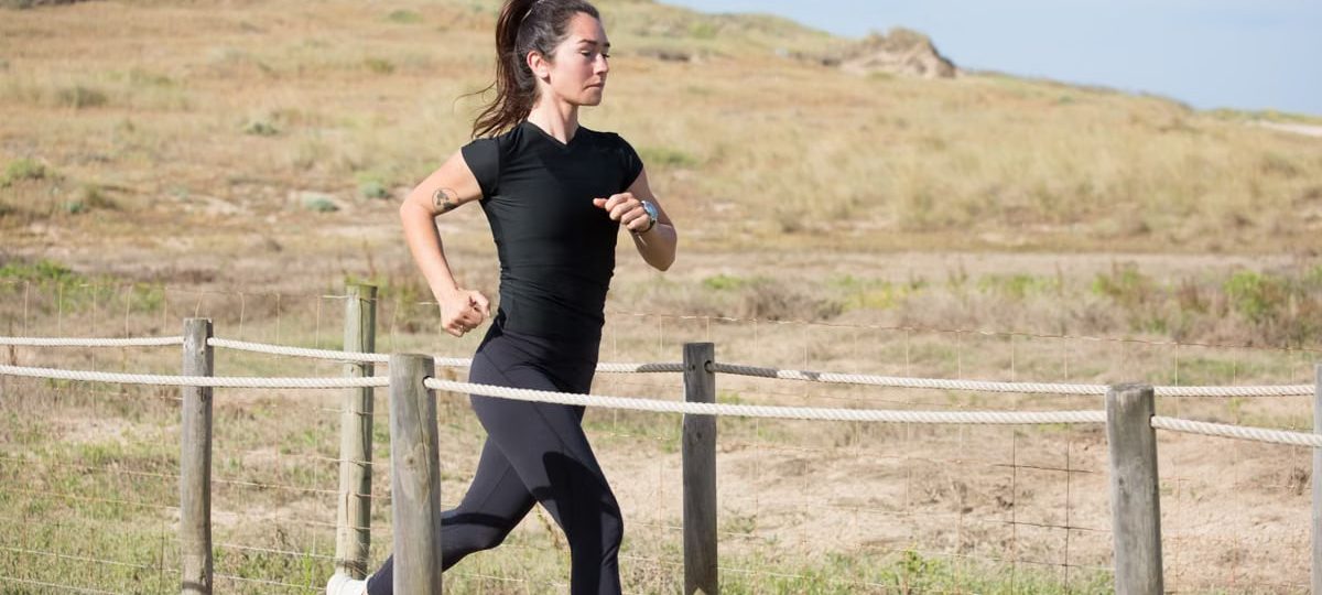 Woman jogging on a sunny day on a wooden path in Portugal, embracing a healthy lifestyle.