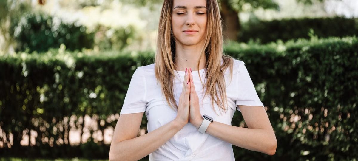 A serene moment of a woman practicing yoga with namaste pose outdoors, embracing mindfulness.